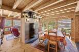 Experience rustic charm in this inviting dining area, featuring a cozy fireplace and a large wooden dining table perfect for family gatherings.