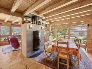 Experience rustic charm in this inviting dining area, featuring a cozy fireplace and a large wooden dining table perfect for family gatherings.