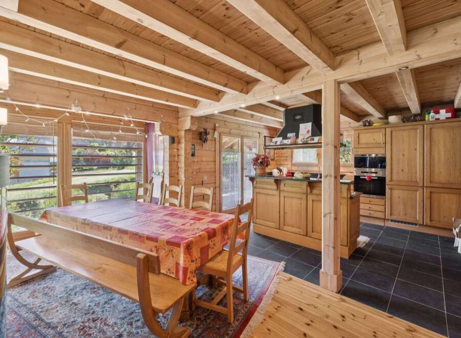 Experience rustic charm in this spacious dining and kitchen area, featuring a large wooden dining table set for gatherings and a fully equipped kitchen with ample cabinetry.