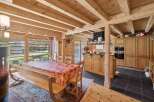 Experience rustic charm in this spacious dining and kitchen area, featuring a large wooden dining table set for gatherings and a fully equipped kitchen with ample cabinetry.