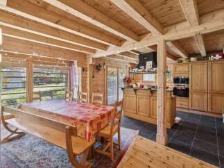 Experience rustic charm in this spacious dining and kitchen area, featuring a large wooden dining table set for gatherings and a fully equipped kitchen with ample cabinetry.