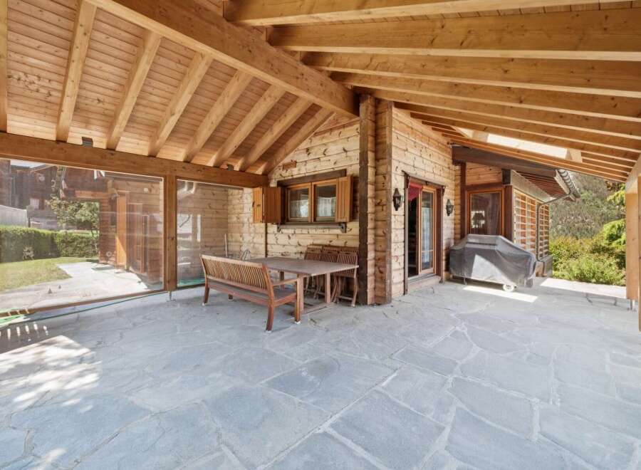 Enjoy outdoor living on this charming covered patio, featuring a rustic wooden dining set perfect for al fresco meals.