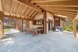 Enjoy outdoor living on this charming covered patio, featuring a rustic wooden dining set perfect for al fresco meals.