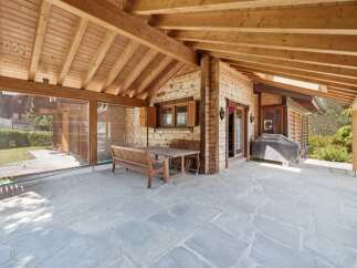 Enjoy outdoor living on this charming covered patio, featuring a rustic wooden dining set perfect for al fresco meals.