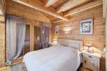 Experience rustic charm in this cozy log cabin bedroom, featuring a comfortable bed adorned with a white knit blanket.