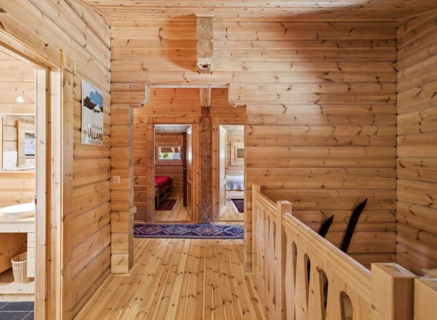 Experience rustic charm in this beautifully appointed log cabin hallway, featuring warm wooden interiors and a charming vintage poster.