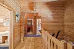 Experience rustic charm in this beautifully appointed log cabin hallway, featuring warm wooden interiors and a charming vintage poster.