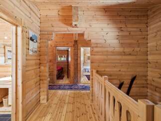 Experience rustic charm in this beautifully appointed log cabin hallway, featuring warm wooden interiors and a charming vintage poster.