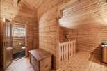 Step into a charming wooden cabin featuring a cozy interior with exposed log walls and a sloped ceiling.