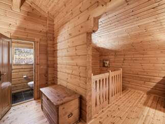 Step into a charming wooden cabin featuring a cozy interior with exposed log walls and a sloped ceiling.