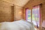 Experience rustic charm in this cozy log cabin bedroom, featuring warm wooden walls and a vaulted ceiling.