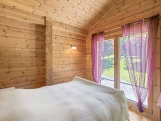 Experience rustic charm in this cozy log cabin bedroom, featuring warm wooden walls and a vaulted ceiling.