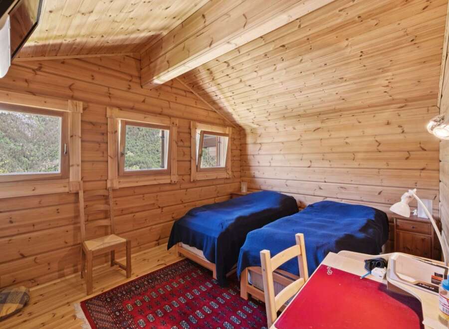 Experience cozy mountain living in this charming log cabin bedroom, featuring two comfortable beds dressed in deep blue linens.