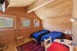 Experience cozy mountain living in this charming log cabin bedroom, featuring two comfortable beds dressed in deep blue linens.