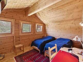 Experience cozy mountain living in this charming log cabin bedroom, featuring two comfortable beds dressed in deep blue linens.