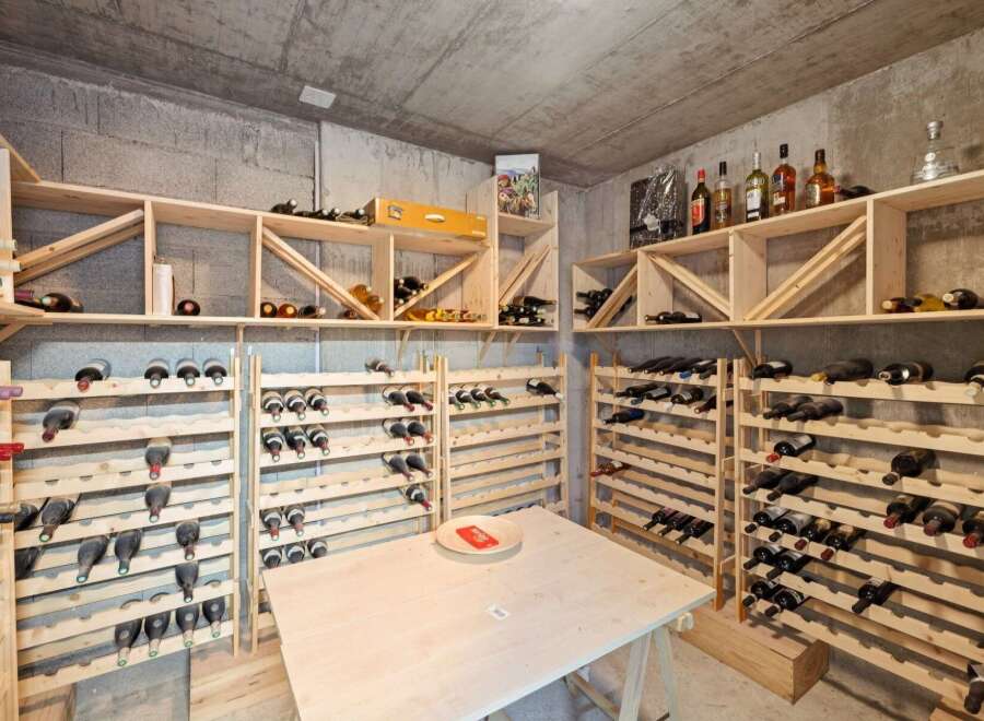 Discover this exceptional wine cellar, featuring extensive wooden shelving designed to store a vast collection of wine bottles.