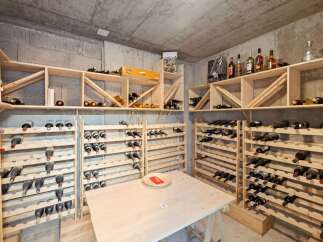 Discover this exceptional wine cellar, featuring extensive wooden shelving designed to store a vast collection of wine bottles.