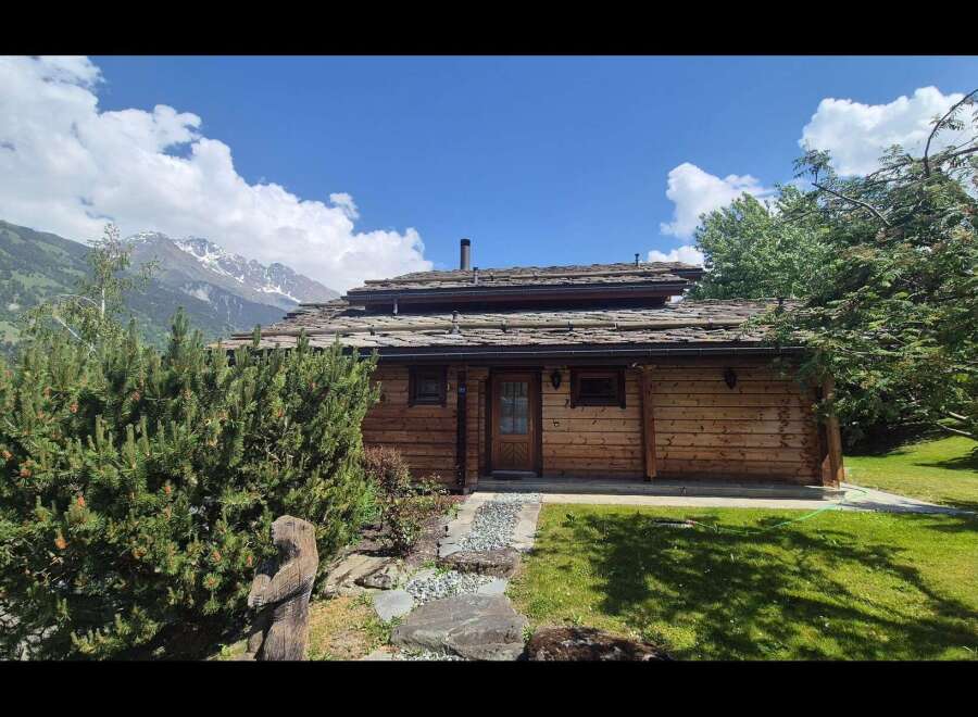 Nestled amidst breathtaking mountain scenery, this charming log cabin offers a rustic retreat with a distinctive slate roof.
