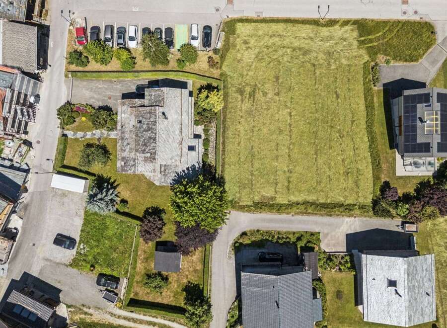 Discover this stunning aerial view showcasing a modern home with solar panels, adjacent to a vast, well-maintained lawn perfect for outdoor activities.