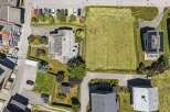 Discover this stunning aerial view showcasing a modern home with solar panels, adjacent to a vast, well-maintained lawn perfect for outdoor activities.