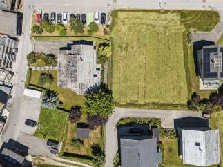 Discover this stunning aerial view showcasing a modern home with solar panels, adjacent to a vast, well-maintained lawn perfect for outdoor activities.