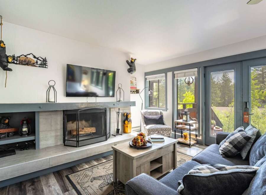 Cozy living room featuring a stone fireplace, a large flat-screen TV, and comfortable seating.