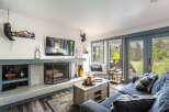 Cozy living room featuring a stone fireplace, a large flat-screen TV, and comfortable seating.