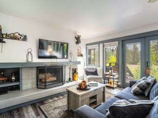 Cozy living room featuring a stone fireplace, a large flat-screen TV, and comfortable seating.