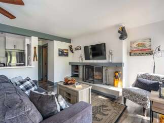 Cozy living room featuring a modern fireplace with a stone surround and a mounted flat-screen TV.