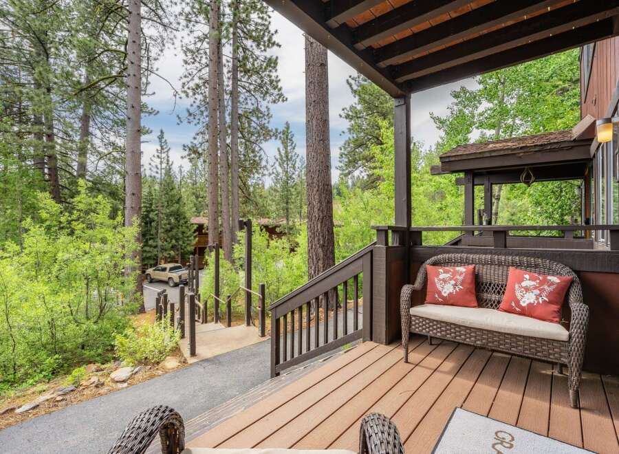 Enjoy the serene mountain setting from this charming covered porch, complete with a cozy wicker loveseat and decorative pillows.