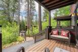 Enjoy the serene mountain setting from this charming covered porch, complete with a cozy wicker loveseat and decorative pillows.