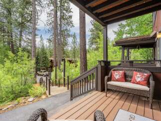 Enjoy the serene mountain setting from this charming covered porch, complete with a cozy wicker loveseat and decorative pillows.