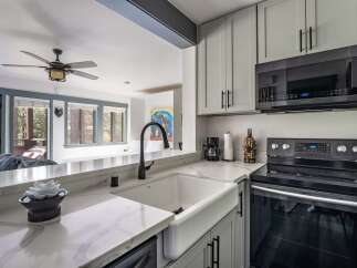 Experience modern comfort in this beautifully updated kitchen, featuring a farmhouse sink and sleek gray cabinetry.