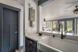 Discover this charming kitchen featuring a farmhouse sink and sleek quartz countertops, perfect for meal preparation.