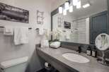 This modern bathroom features a sleek gray countertop with an undermount sink and a black faucet.
