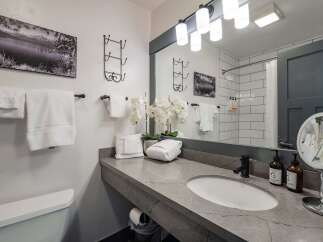 This modern bathroom features a sleek gray countertop with an undermount sink and a black faucet.