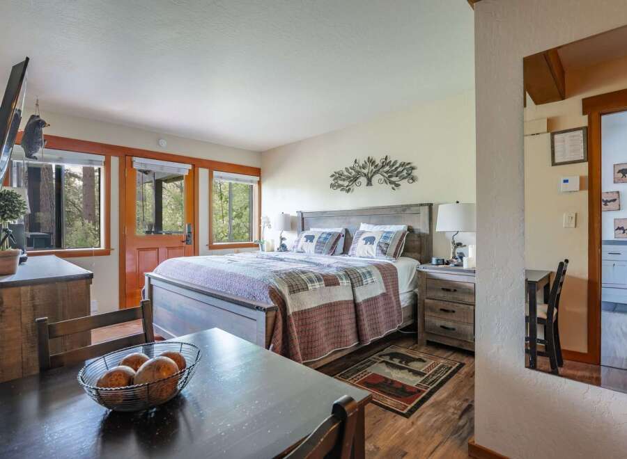 Experience rustic charm in this cozy bedroom featuring a comfortable queen-size bed adorned with bear-themed pillows and a patchwork quilt.