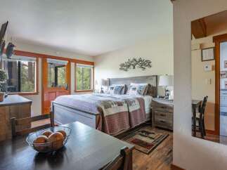 Experience rustic charm in this cozy bedroom featuring a comfortable queen-size bed adorned with bear-themed pillows and a patchwork quilt.