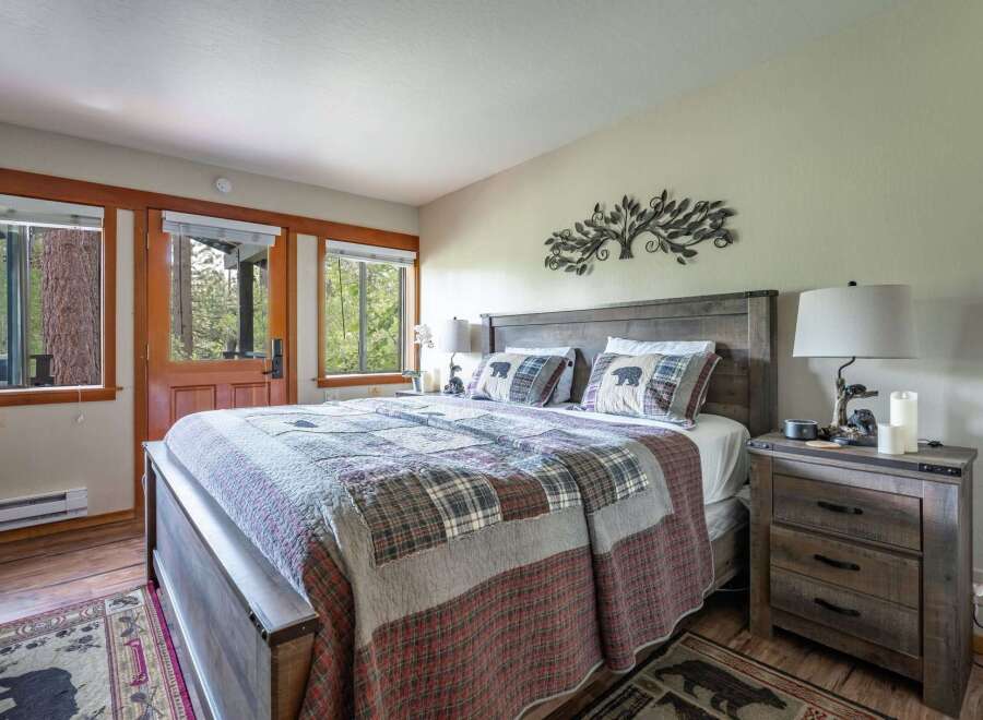 Experience rustic charm in this cozy bedroom, featuring a comfortable queen-size bed adorned with a charming bear-themed quilt and pillows.