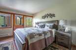Experience rustic charm in this cozy bedroom, featuring a comfortable queen-size bed adorned with a charming bear-themed quilt and pillows.