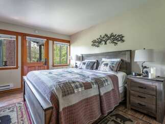 Experience rustic charm in this cozy bedroom, featuring a comfortable queen-size bed adorned with a charming bear-themed quilt and pillows.