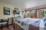 Experience cozy mountain living in this charming bedroom featuring a plush, plaid quilt on a large bed.