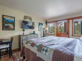 Experience cozy mountain living in this charming bedroom featuring a plush, plaid quilt on a large bed.