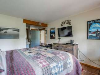 Experience comfort and style in this charming room, featuring a cozy bed adorned with a rustic quilt and decorative pillows.