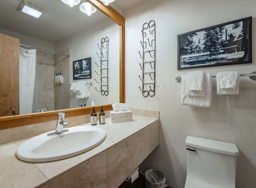 This charming bathroom features a spacious vanity with a marble countertop, a modern sink, and ample storage.