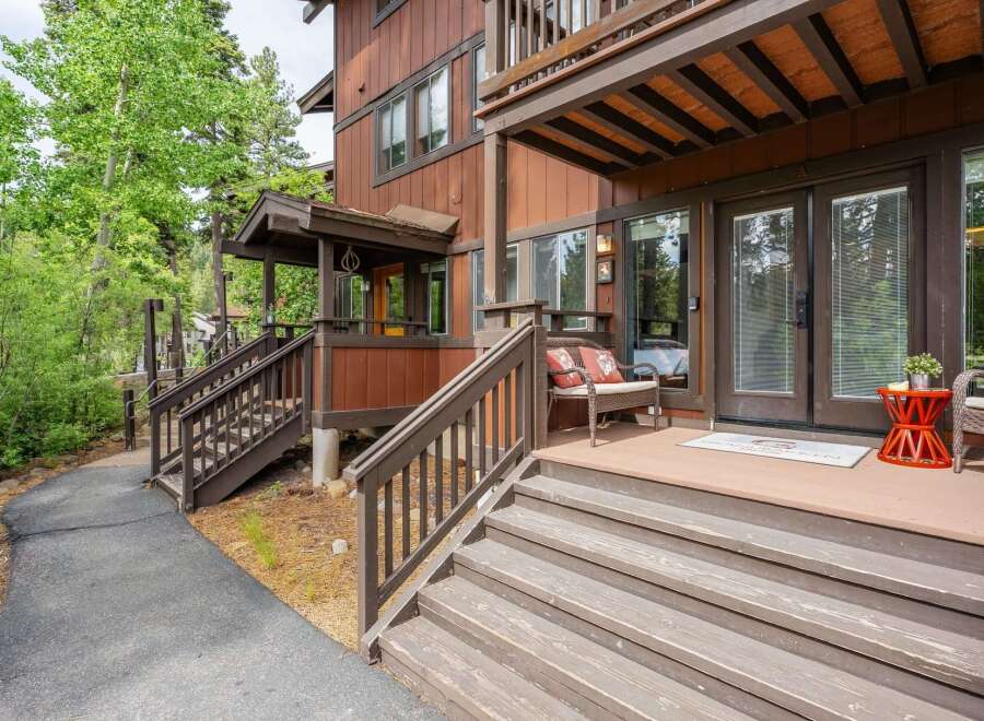 Discover this charming mountain retreat featuring a welcoming porch with comfortable seating and a vibrant orange accent table.