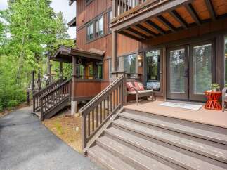 Discover this charming mountain retreat featuring a welcoming porch with comfortable seating and a vibrant orange accent table.