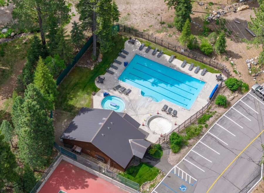 Experience resort-style living with this stunning aerial view showcasing a large swimming pool and a separate hot tub, perfect for relaxation and recreation.