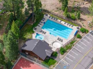 Experience resort-style living with this stunning aerial view showcasing a large swimming pool and a separate hot tub, perfect for relaxation and recreation.