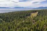 Nestled amidst a dense pine forest, this property offers a serene retreat with stunning views of a vast lake and distant snow-capped mountains.